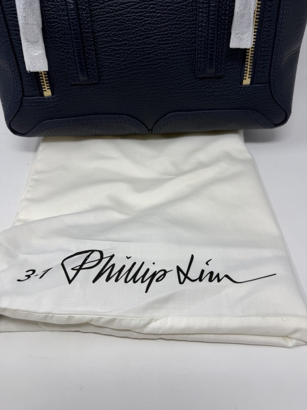 3.1 Phillip Lim Pashli medium satchel in navy pebbled leather, front flap with the dust bag behind