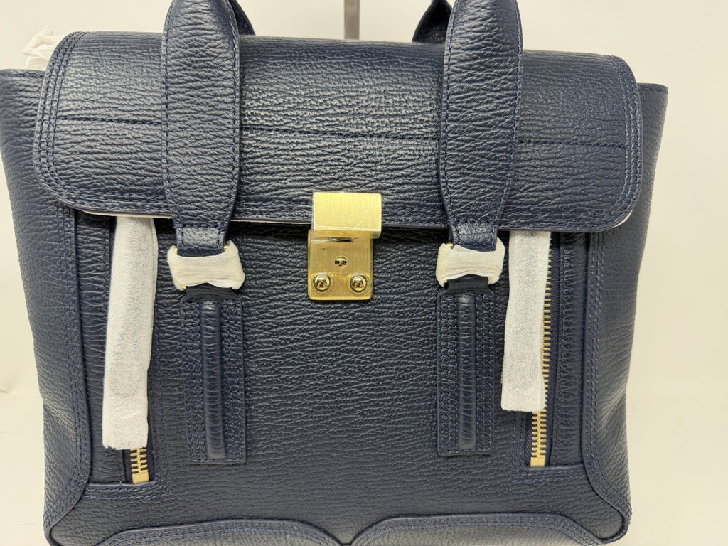 3.1 Phillip Lim Pashli medium satchel in navy pebbled leather, front view showing the push-lock and front zips