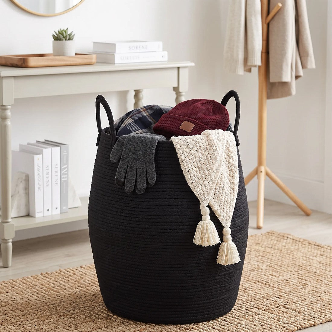 Black rope basket holding a hat, gloves and a knitted scarf in a hallway