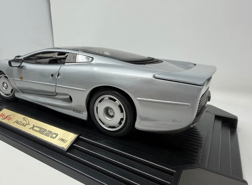Silver Maisto Jaguar XJ220 1992 diecast model car with detailed features, displayed alongside its original box.