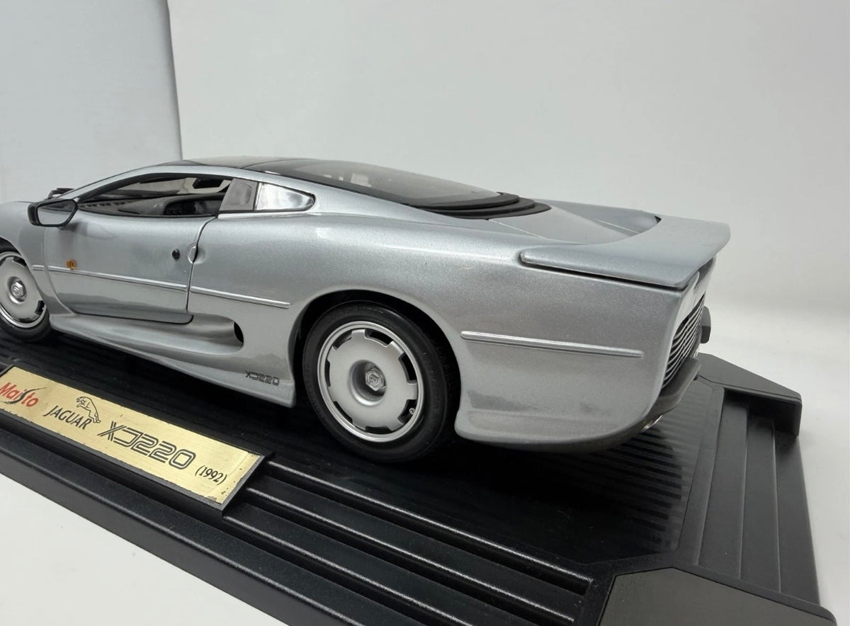 Silver Maisto Jaguar XJ220 1992 diecast model car with detailed features, displayed alongside its original box.