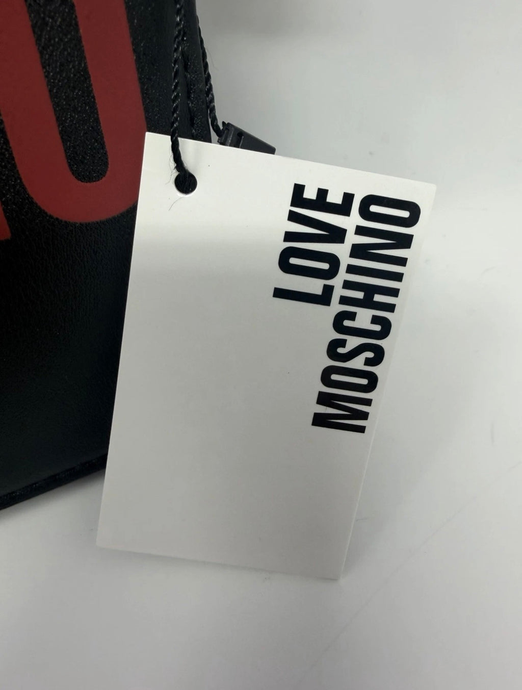 Love Moschino black shoulder bag with cow appliqué and chain strap, stylish handbag with bold design.