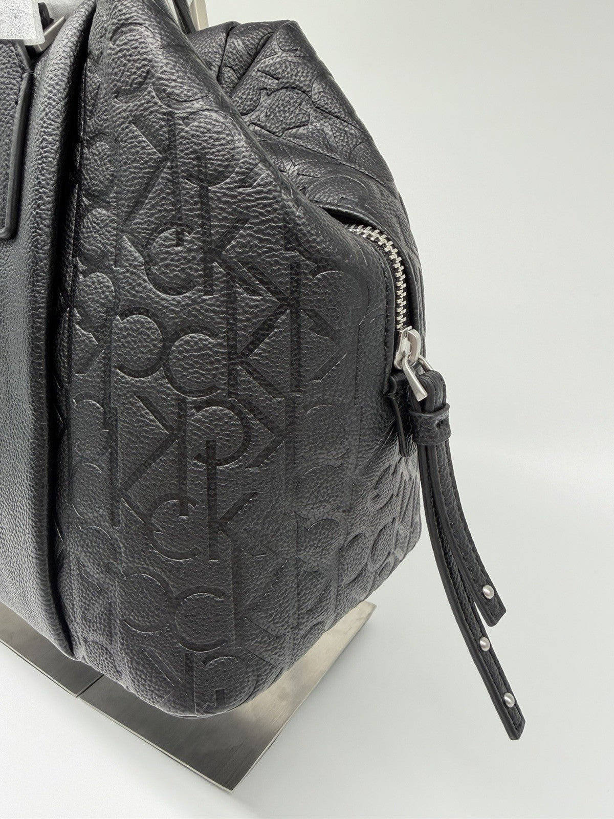Black Calvin Klein Misha duffle bag with CK monogram, strap, dust bag, and tags visible in the image.