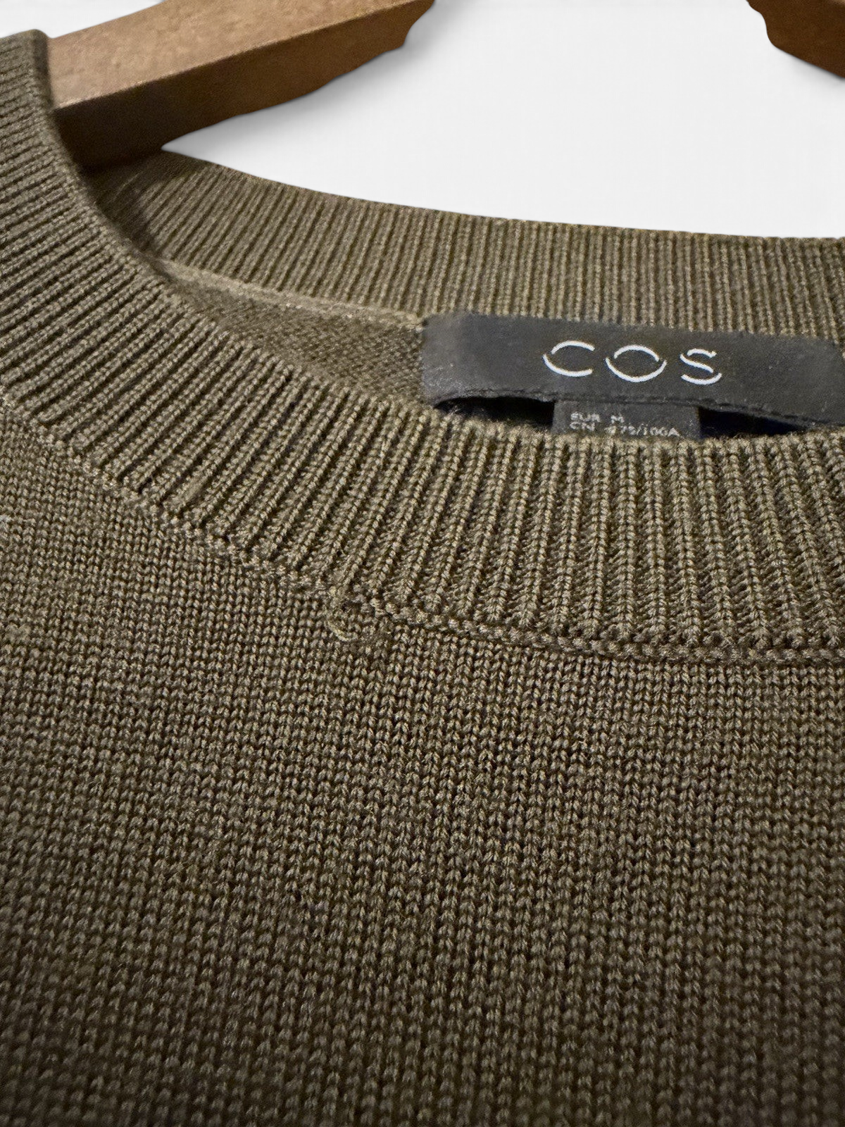 Men's COS olive green wool crew neck jumper, size M, pre-owned, with a close-up view of the textured knit fabric.