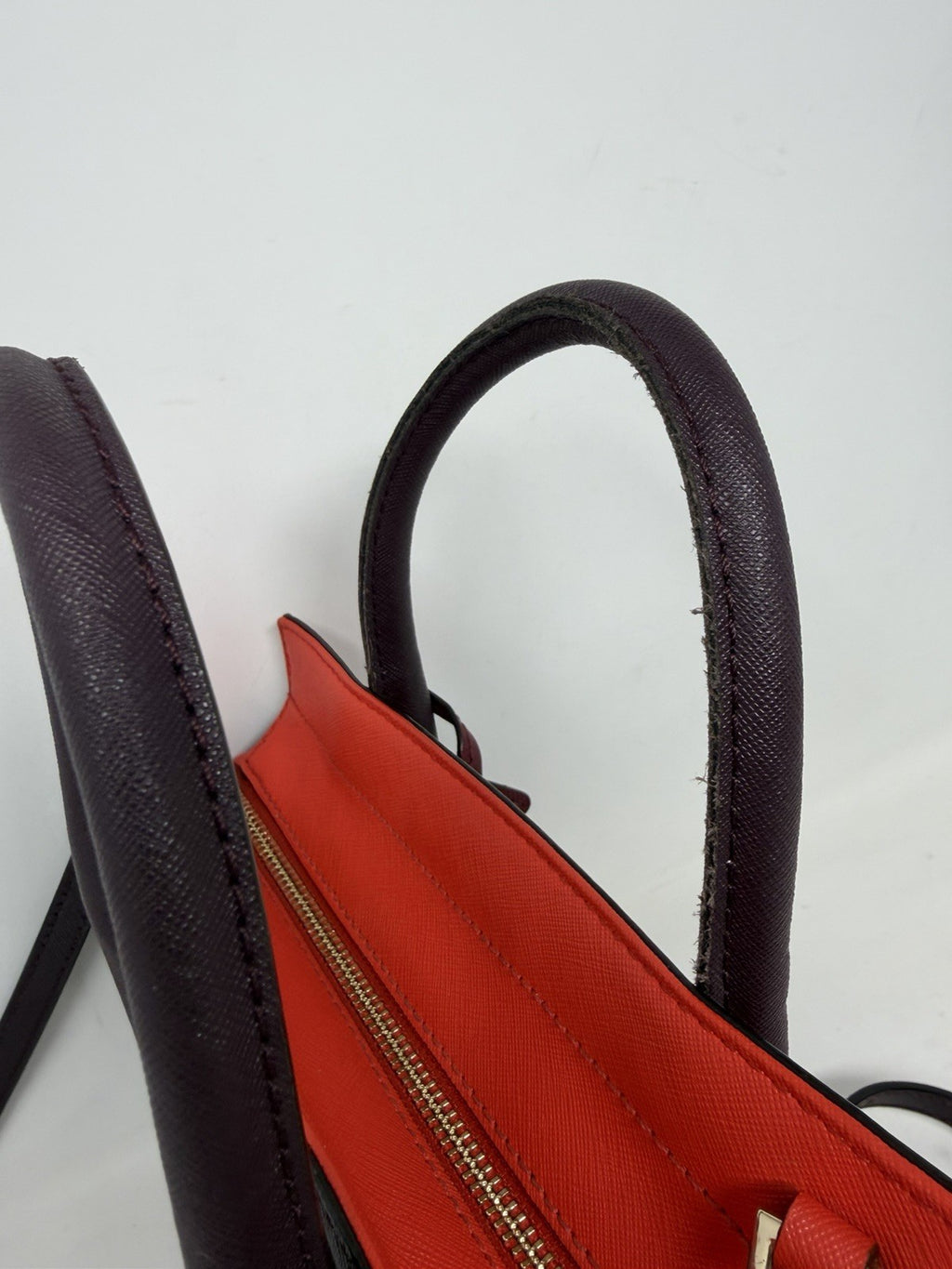 Kate Spade New York Small Cameron leather satchel in burgundy and red, featuring saffiano texture and polished gold hardware.