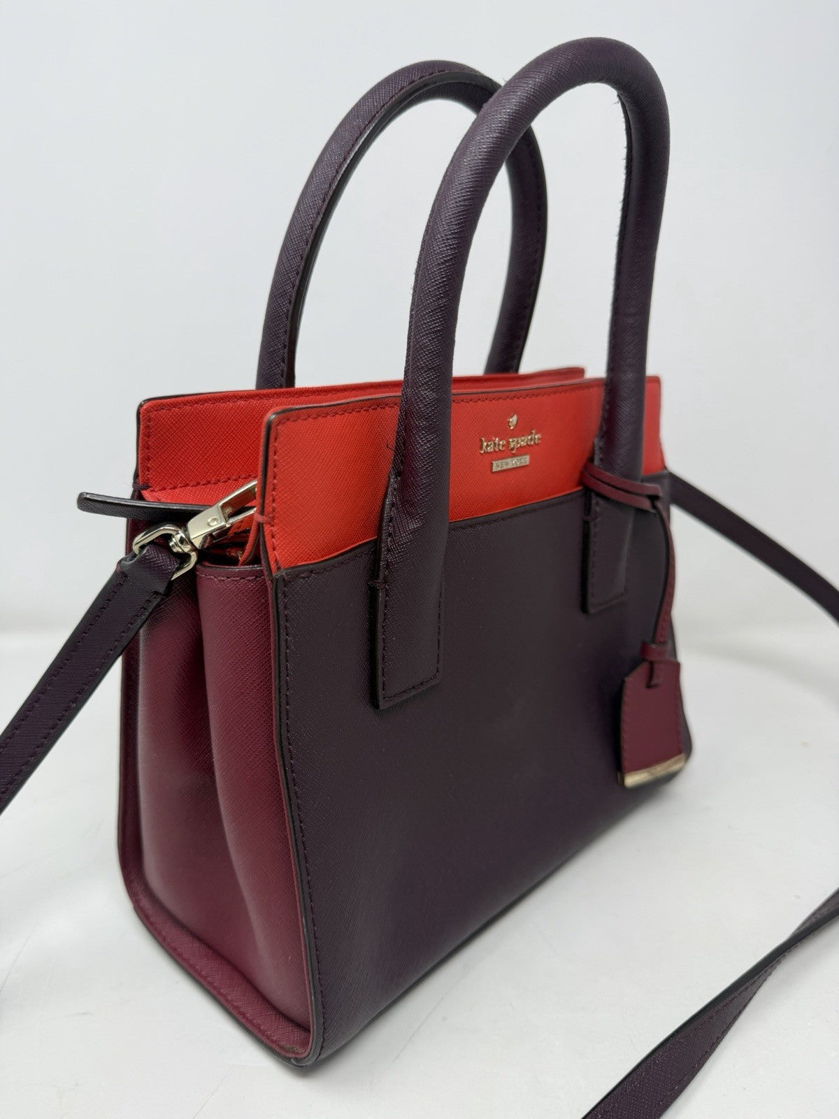 Kate Spade New York Small Cameron leather satchel in burgundy and red with gold hardware, showcasing its structured design.