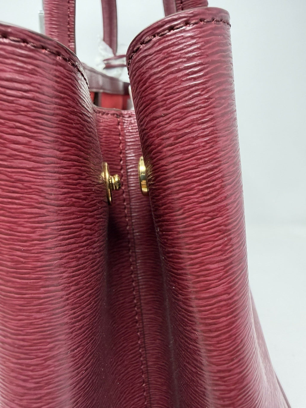 Close-up of the handle fixings and gold-tone studs on the rosewood tote