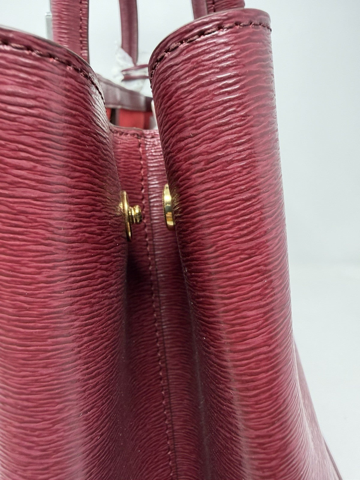 Close-up of the handle fixings and gold-tone studs on the rosewood tote