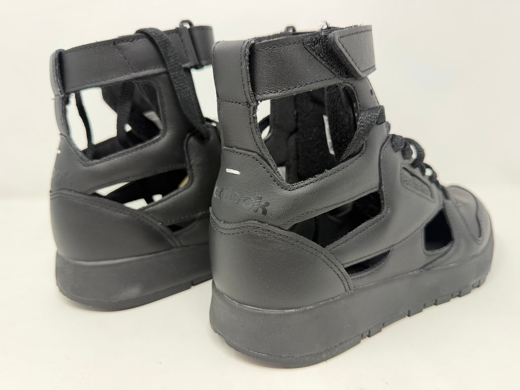 Black Maison Margiela × Reebok Classic Leather Tabi high-top trainers, UK 6.5, featuring distinctive split-toe design, on a plain background.